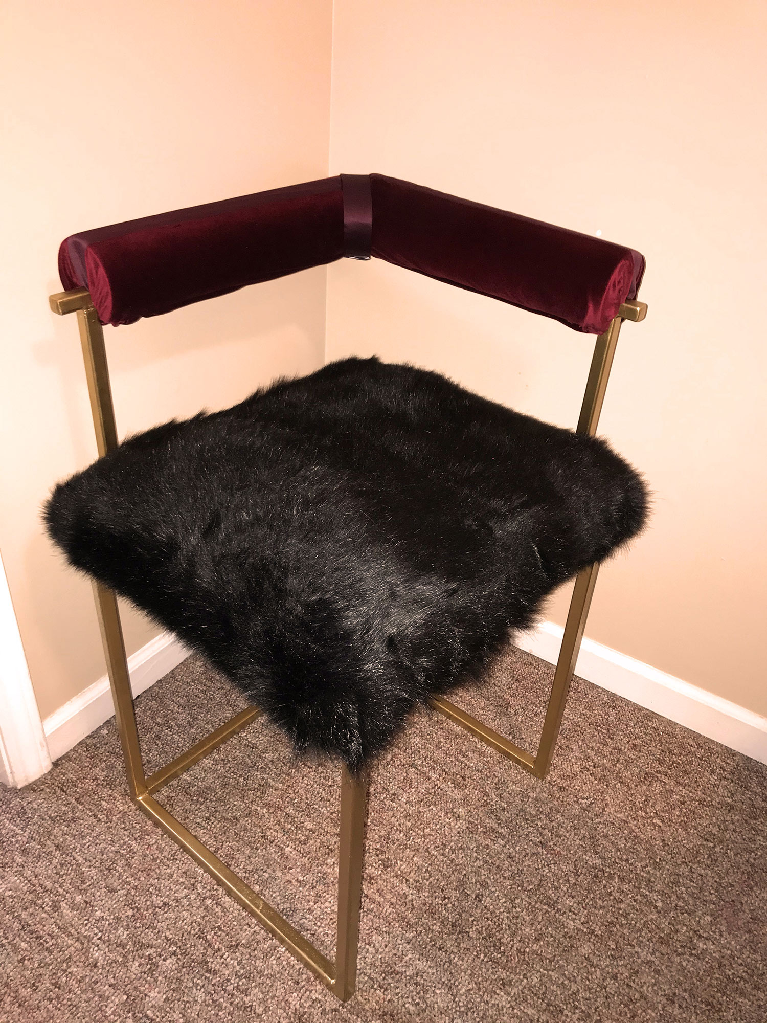 chair with gold legs and black fuzz on seat