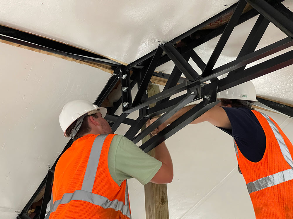 building construction science students work on the inside metal piece of a roof truss