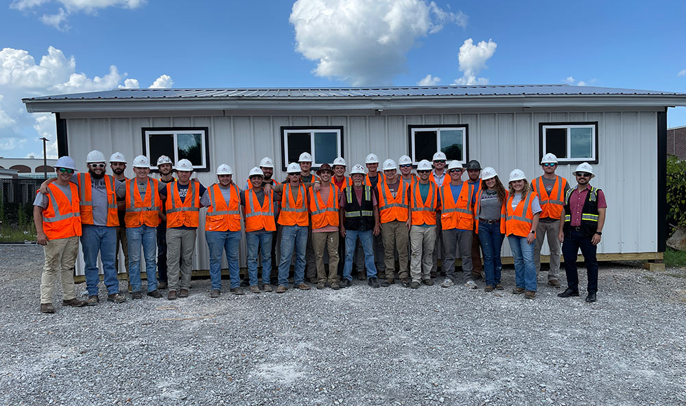 MSU building construction science group gathers for photo in PPE in front of summer build