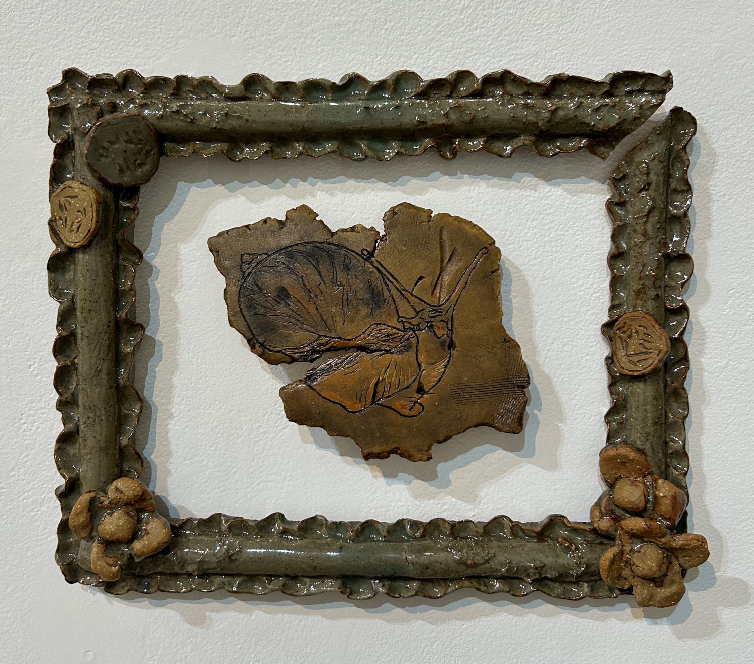 ceramic piece with snail carved on a flat piece framed by ceramic