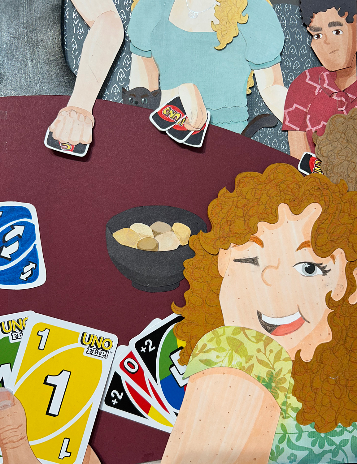 Image of a cut-paper scene. Four figures sit around a restaurant booth table playing UNO. The figure in the front right looks back at the viewer and winks.