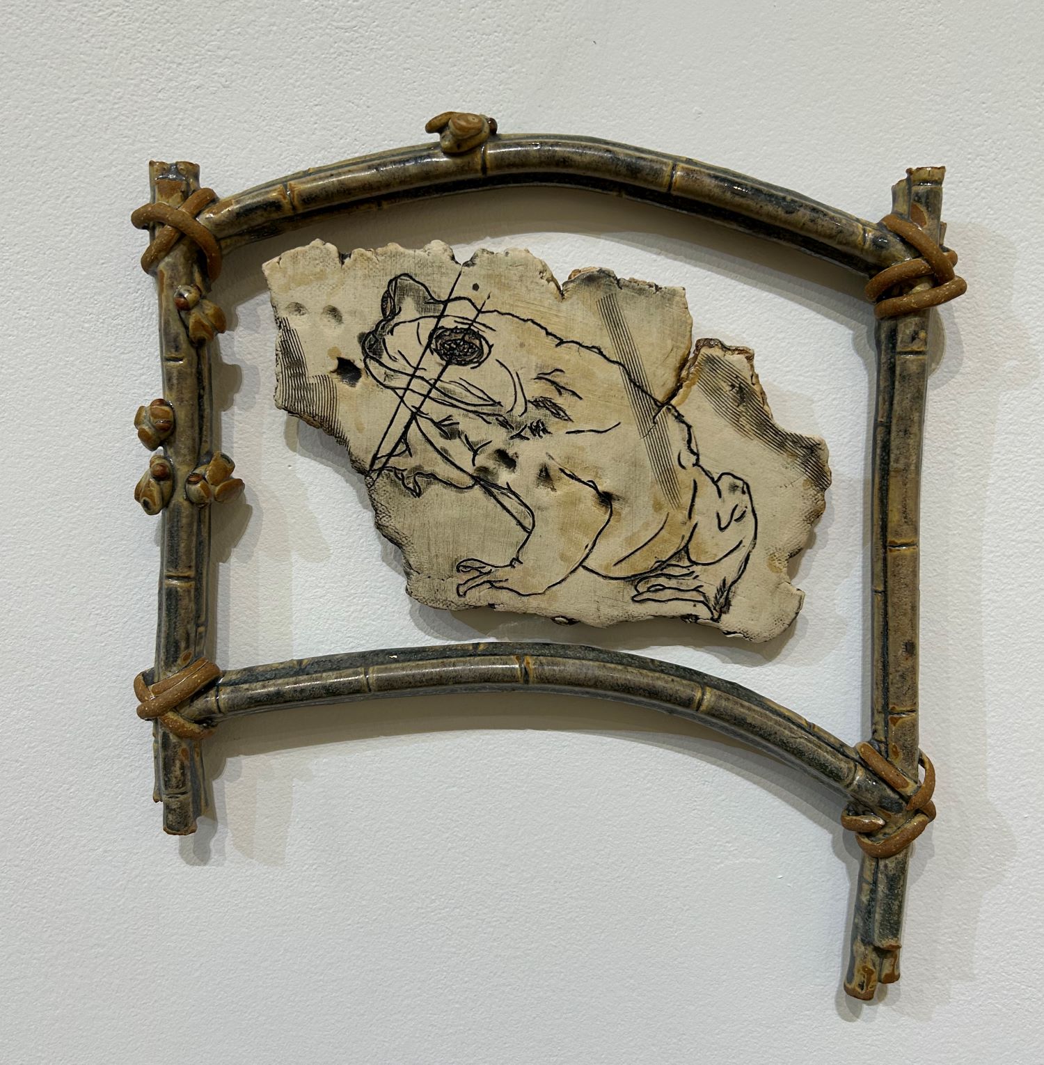 ceramic piece of a frog surrounded by a frame made of clay