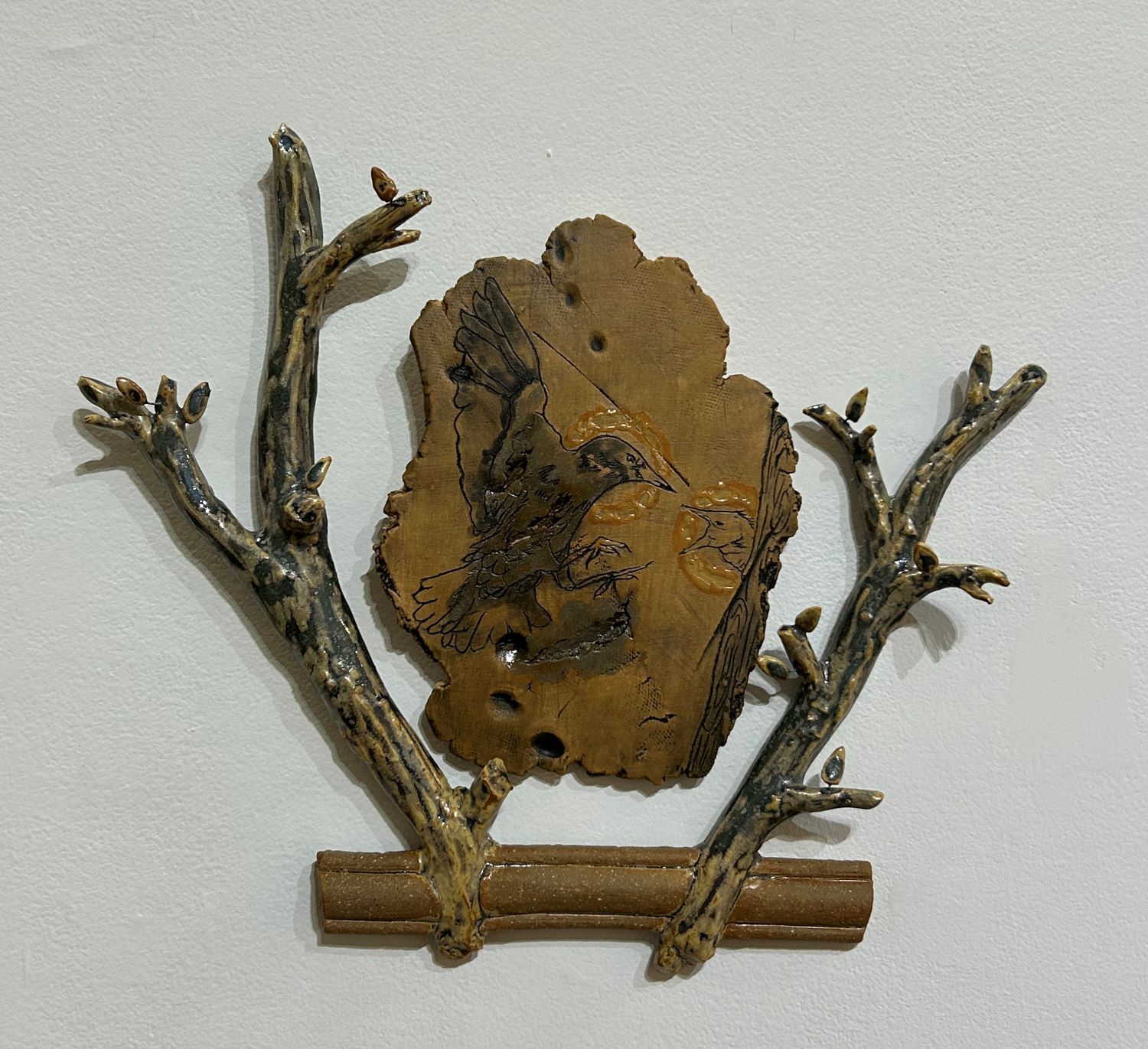 ceramic piece of a bird with branches made with clay surrounding it