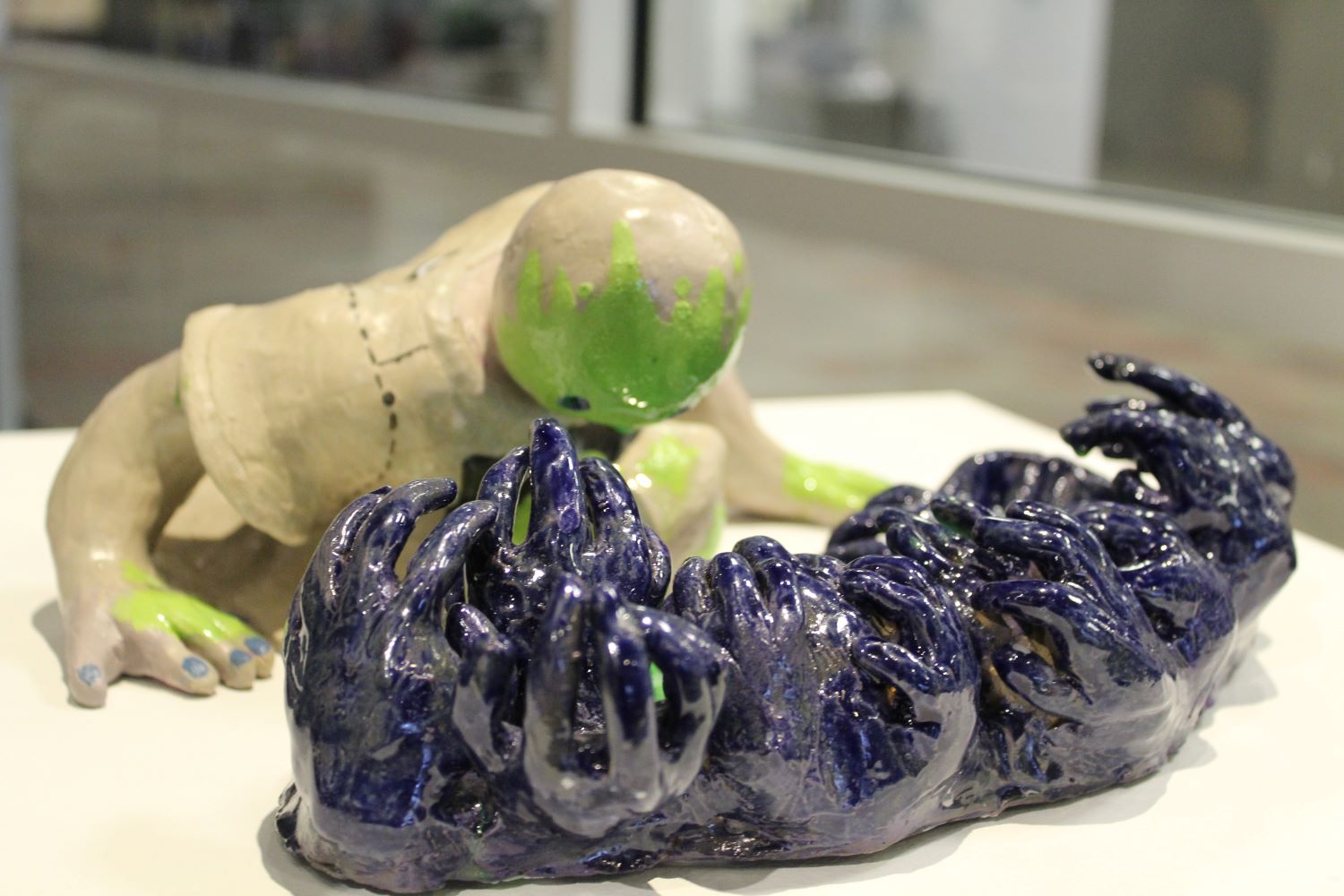 ceramic piece of a human looking at a group of hands